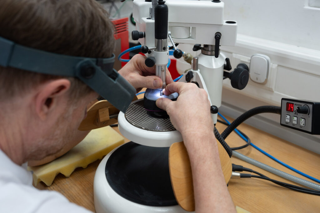 Ein Mitarbeiter fertigt Zahnersatz im Labor an.